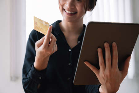 Asian woman making online payment using laptop and credit card for shopping at home.の写真素材