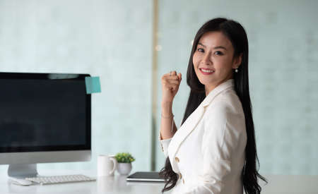 Portrait of excited business woman smiling and raised hands up celebrate , successful winner businesswoman look at cameraの写真素材