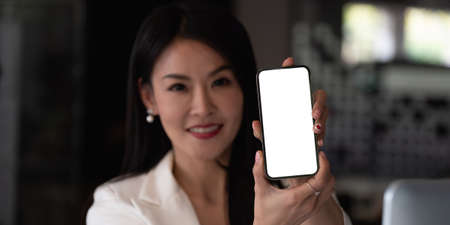 Asian businesswoman showing a blank smartphone screen. Focus on smartphone.の写真素材