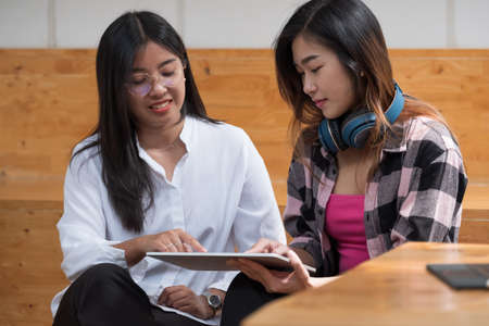 Happy young asian student girls studying at home with digital tablet computers.の写真素材