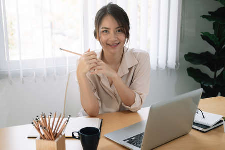 Portrait of young asian woman using laptop at home officeの写真素材