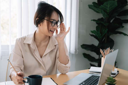 Young asian female student with glasses study with a laptop for online learning at homeの写真素材