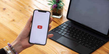 CHIANG MAI, THAILAND - MAR 7, 2021: Woman hand holding Apple iPhone 12 with App YouTube provides streaming media and video on the screenのeditorial素材
