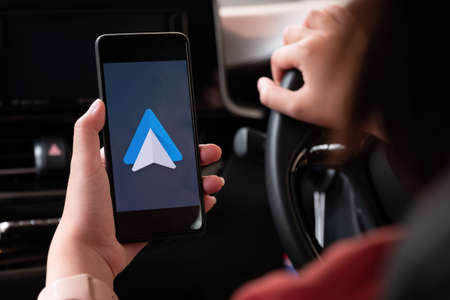 CHIANG MAI , THAILAND - MAR 28, 2021: Close up to female driving and using navigation appliction Google Android Auto. An illustrative editorial image.のeditorial素材