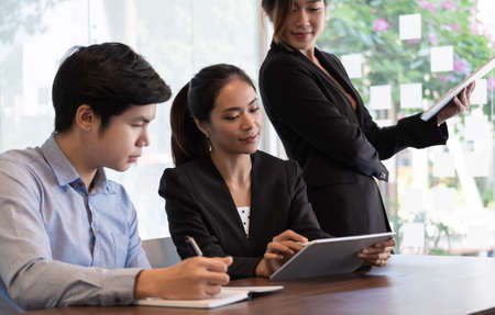 Coworkers team at work. Group of young business people in trendy working together in creative office with digital tebletの写真素材