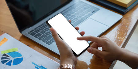 Man using smartphone blank screen frameless modern design while financial working at officeの写真素材