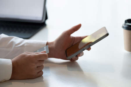 Close up hand of woman shopping online with credit card using smart phone at cafeの写真素材