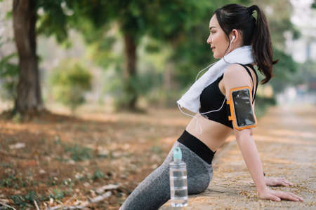 Athletic asian woman resting after a hard training in the mountains at sunset. Sport tight clothesの写真素材