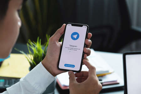 CHIANG MAI, THAILAND, APR 06, 2021 : Woman hand holding iPhone X with social networking service Telegram on the screen. iPhone 10 was created and developed by the Apple inc.のeditorial素材