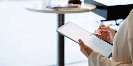 Close uo businesswoman holds pen stylus drawing on digital tablet on workplace