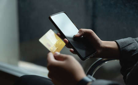 Close up woman at home shopping online with credit card and smart phone