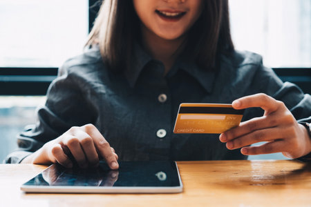 Young woman holding credit card and using tablet computer. Online shopping conceptの写真素材