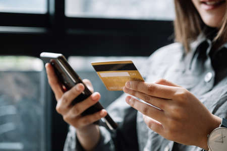 Close up woman at home shopping online with credit card and smart phoneの写真素材