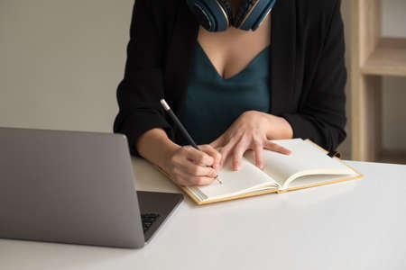 Woman make notes sit at work desk while study online watching webinar podcast on laptop listening learning education course conference, elearning concept.の写真素材