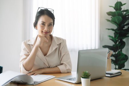 Portrait of businesswoman with laptop while checklist on a document at her office.の写真素材