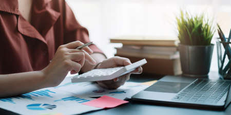 Business woman using calculator for do math finance on wooden desk in office, tax, accounting, statistics home accounring concept.の写真素材