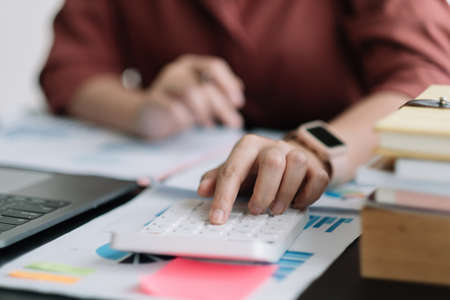 Business woman using calculator for do math finance on wooden desk in office, tax, accounting, statistics home accounring concept.の写真素材