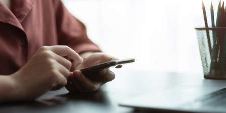 Close up hand of woman using smart phoneの写真素材