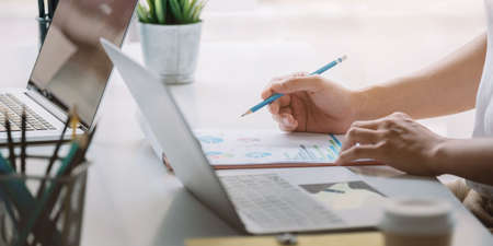Close up Businessman hand holding pen and pointing at financial paperwork, financial charts to analyze profit conceptの写真素材