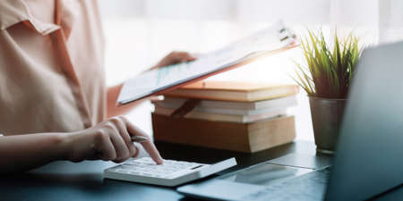 Business woman using calculator for do math finance on wooden desk in office, tax, accounting, statistics home accounring concept.の写真素材