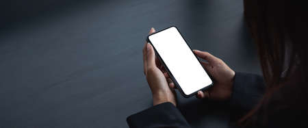 cell phone blank white screen mockup. woman hand holding texting using mobile on desk at office.background empty space for advertise.の写真素材