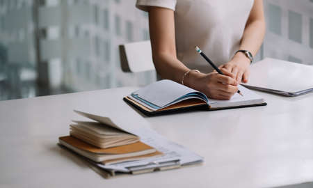 Close up of a woman writer hand writing in a notebook at homeの写真素材