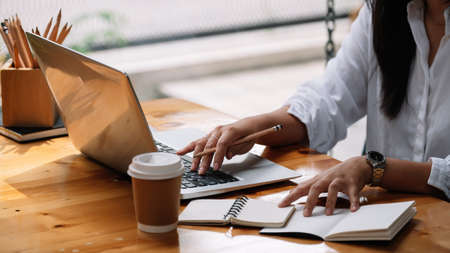 Cropped photo of woman writing making list taking notes in notepad working or learning on laptop indoors- educational course or training, seminar, education online concept.の写真素材