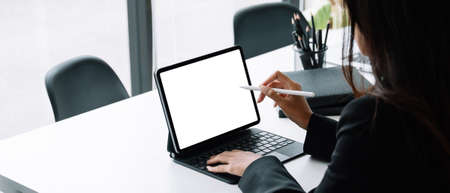 Businesswoman working with a stylus pen on a digital tablet with a laptop computer in a modern officeの写真素材