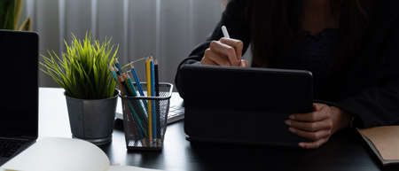 Close up business woman holds pen stylus with digital tablet at office.の写真素材
