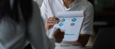 Close up business people discussing the charts and graphs showing the results of their successful teamwork.の写真素材