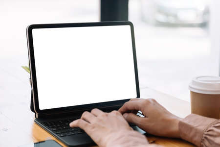 Close up hand of woman typing on smart tablet with blank white screen on tableの写真素材
