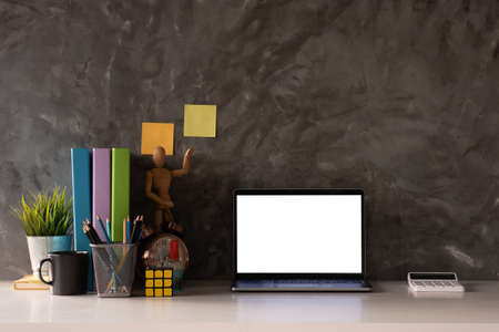 Cropped shot of workspace with mock-up laptop with white blank screen, Home interior or office background.の写真素材