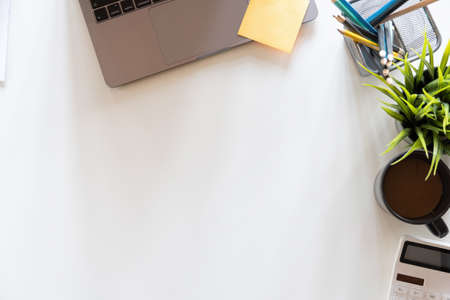 Top view of workplace with copy space, calculator and plant potted on white desk background, Accounting workplace conceptの写真素材