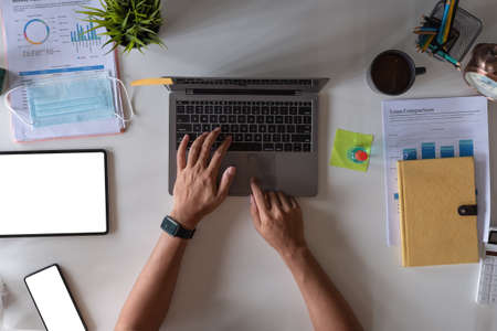 Top view of male hands working on modern laptop. Office desktop on white background, business accounting concept.の写真素材