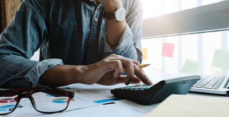 Business woman working in finance and accounting Analyze financial budget with calculator and laptop computer in the officeの写真素材