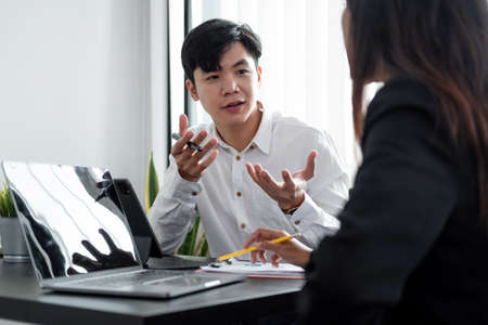 Young asian male mentor coach worker talking to female coworker teaching intern having business...