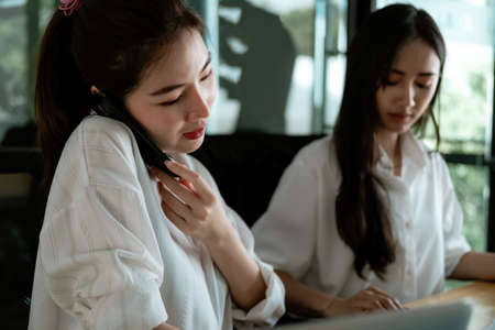 Busy businesswoman calling mobile phone to consult for business financial at officeの写真素材