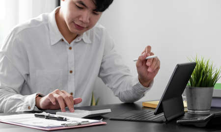 man accountant working with digital tablet computer and calculator for business and financial expense at home officeの写真素材