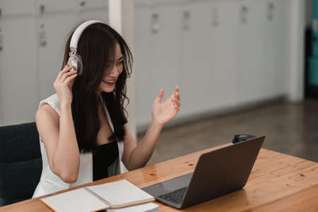 Smiling girl student wear wireless headphone study online with teacher, happy young asian woman...