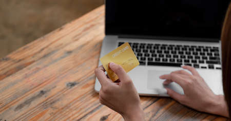 Hands holding credit card and using laptop. Online shopping at coffee shop cafe