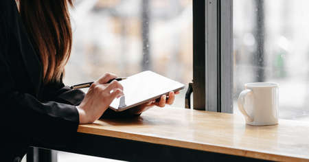 Close up business woman working with digital tablet on wooden desk with coffee morningの写真素材