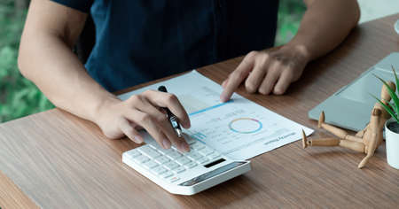 Businessman working with financial data hand using calculator and writing make note with calculate....