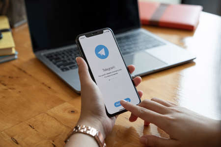 CHIANG MAI, THAILAND, JAN 23, 2021 : Woman hand holding iPhone 12 with social networking service Telegram on the screen. iPhone 12 was created and developed by the Apple inc.のeditorial素材