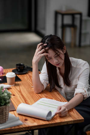 Stressed asian business woman working with marketing report. business financial concept.の写真素材