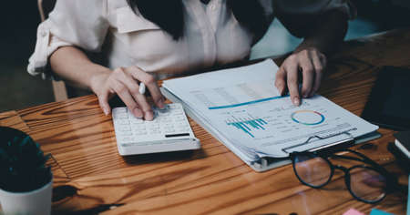 businesswoman working on desk with calculator with financial chart report in office. concept...