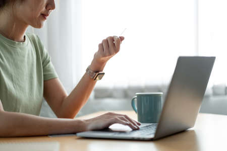 Close up woman hands holding a credit card and using computer keyboard for online shopping at home.