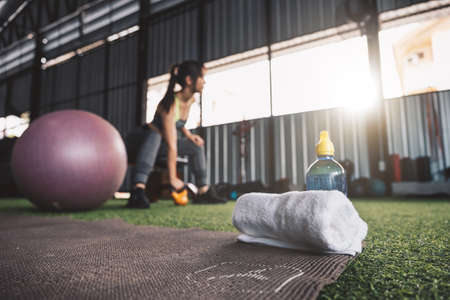 Selective focus towel and water bottle with woman workout fitness background.の写真素材