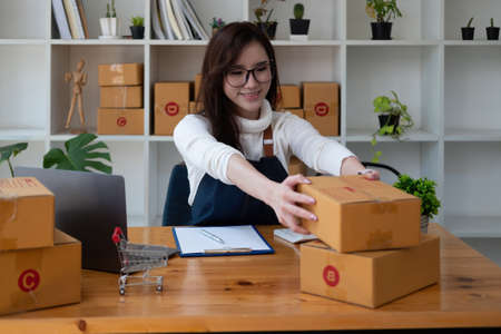 Starting Small business entrepreneur SME freelance,Portrait young woman working at home office, BOX,smartphone,laptop, online, marketing, packaging, delivery, SME, e-commerce concept.の写真素材