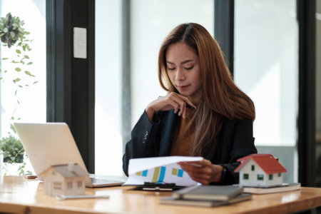 Asian business woman working for interest, taxes and profits to invest in real estate and home buyingの写真素材