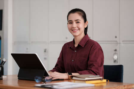 Portrait of attractive entrepreneur asian woman, business woman looking at camera while working for accounting finance with laptop computer.の写真素材